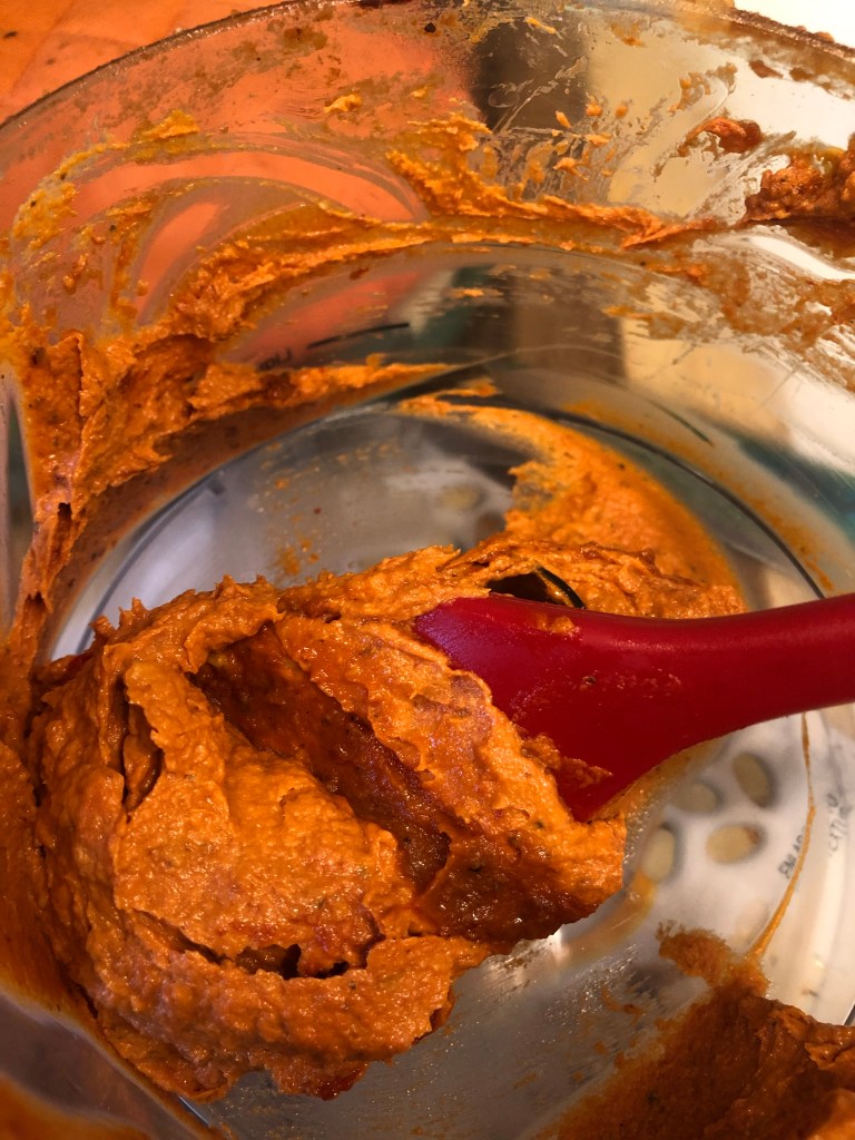 red sauce in a food processor with a red spatula/rubber scraper in it.